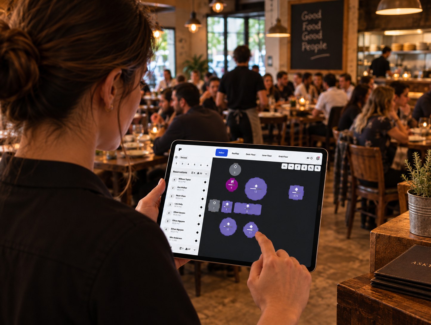 A staff member checking the live floor view on a tablet in a busy venue, tables shown by colour and status