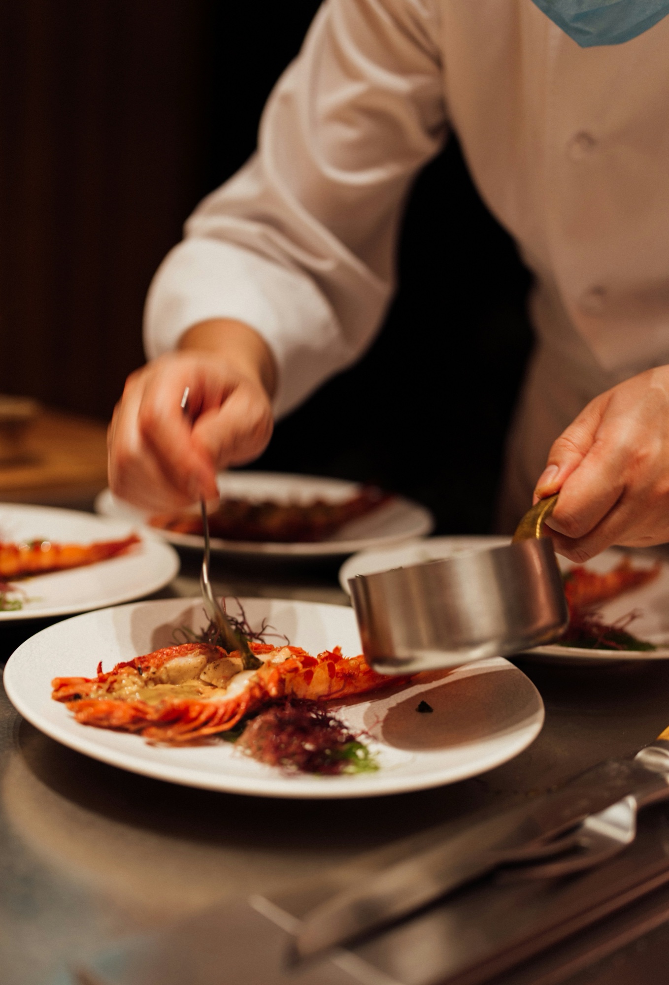 A chef finishing a plated seafood dish